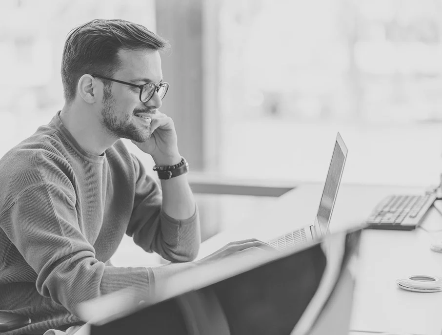 A person taking notes in front of a laptop